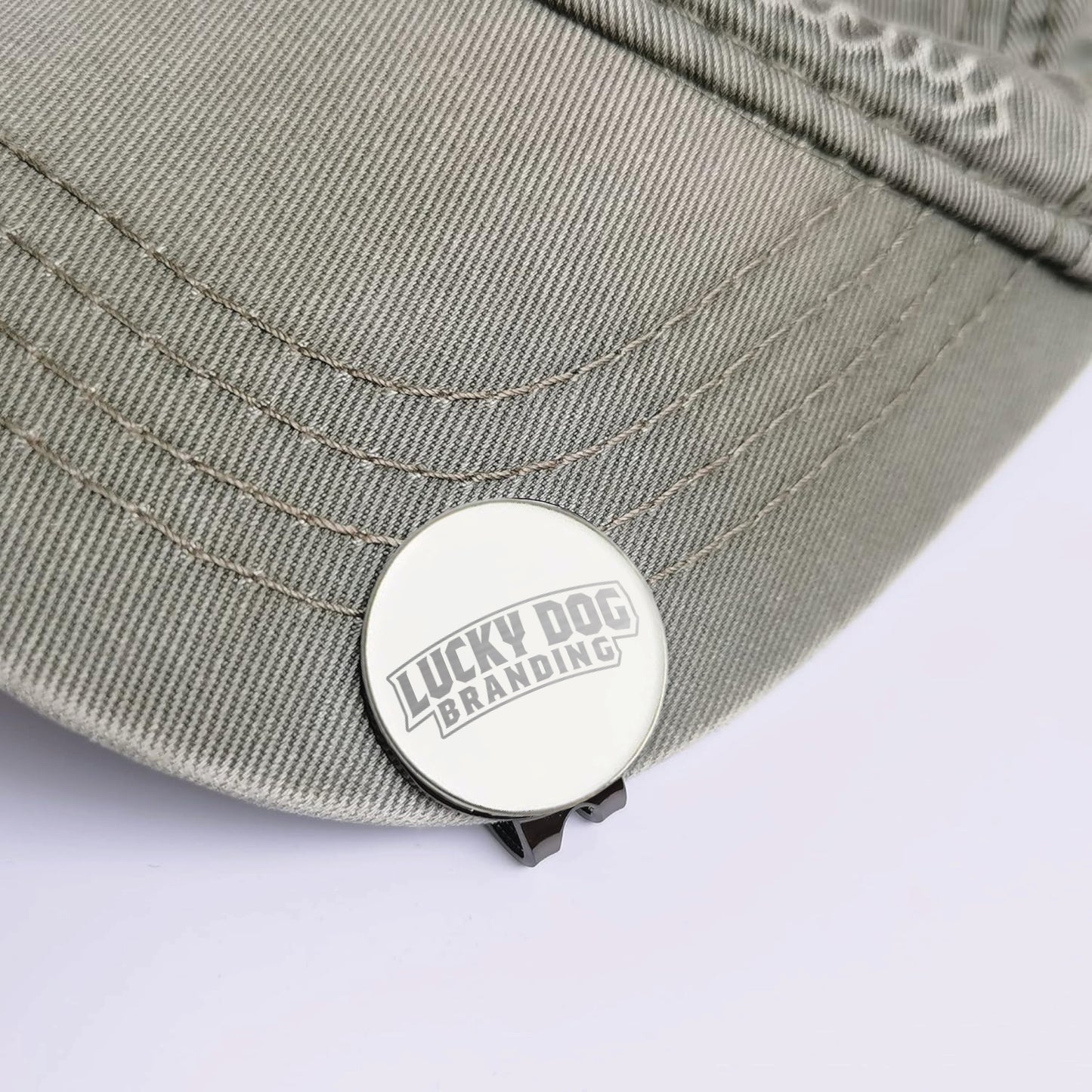 Close-up of a custom laser engraved golf ball marker and hat clip showing detailed engraving and durable metal finish