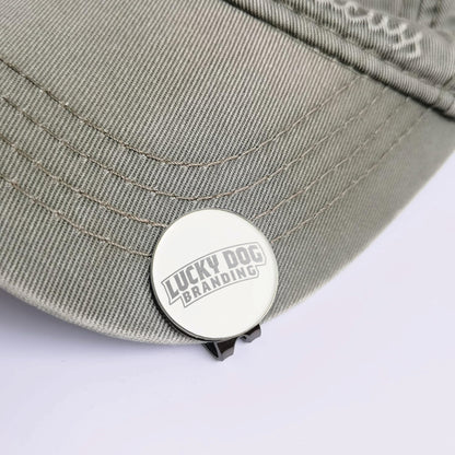 Close-up of a custom laser engraved golf ball marker and hat clip showing detailed engraving and durable metal finish