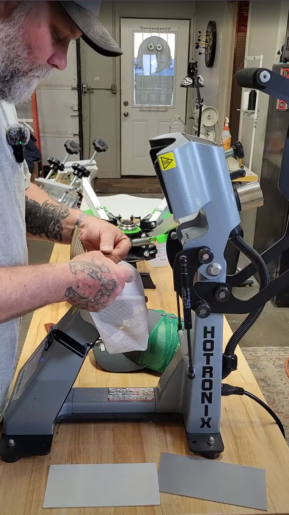 Person working with a Hotronix IQ 360 on a workbench pressing a custom leather patch hat.
